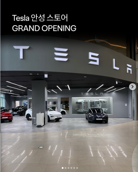 테슬라 안성 스토어 전경, 천장의 대형 TESLA 로고 월사인과 그랜드 오프닝을 알리는 전시 차량들
