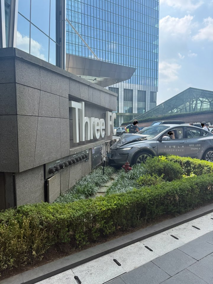 Three IFC 건물 사인 옆 화단과 기둥에 부딪힌 테슬라 시승차 앞부분